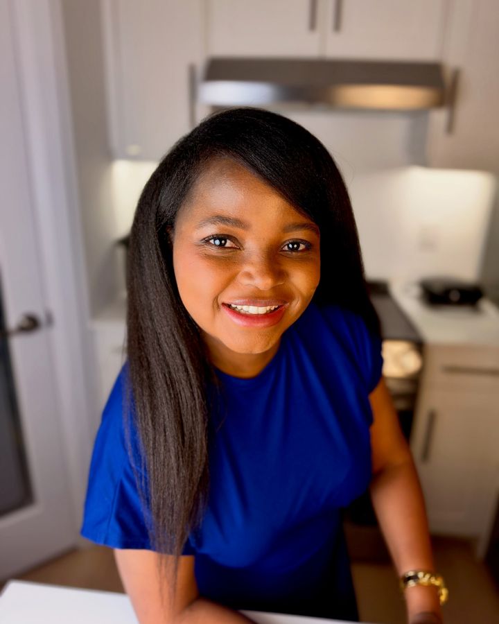 Frida Lutonda in a cobalt dress at home, smiling at the camera