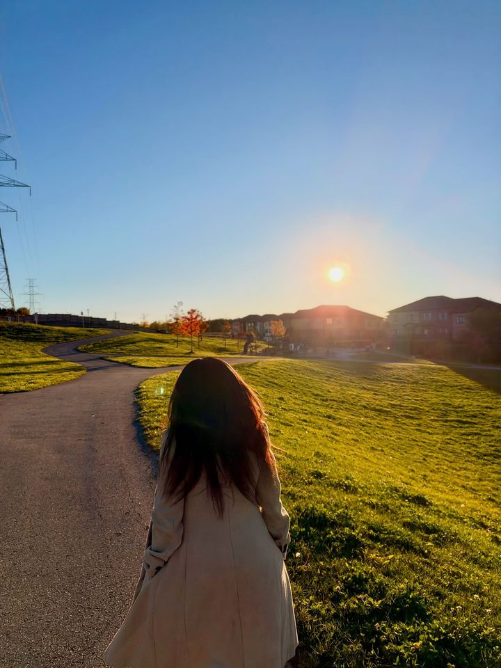 Frida walking down a park path toward the low sun